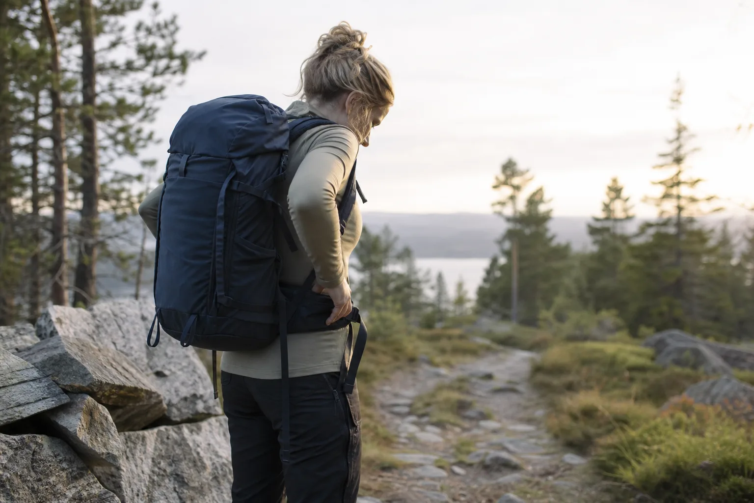 Kvinna justerar höftbältet på en ryggsäck med vinklat bälte inför en vandringstur