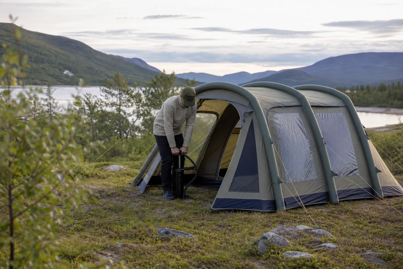Person pumpar upp luftbalkarna på ett stort familjetält på en campingplats
